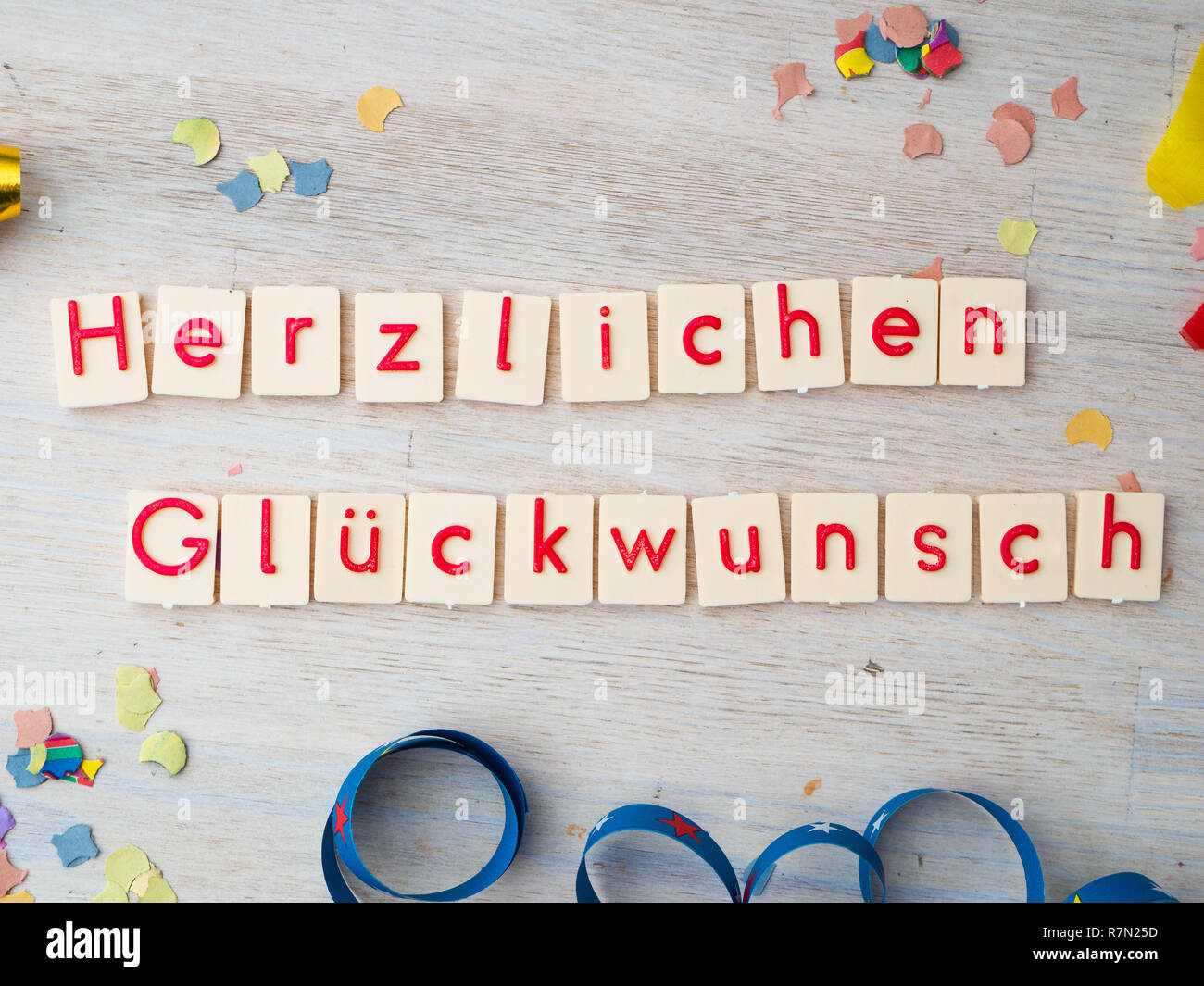 Herzlichen Glückwunsch (congratulations) lettering with party supplies on wooden background, concept image Stock Photo