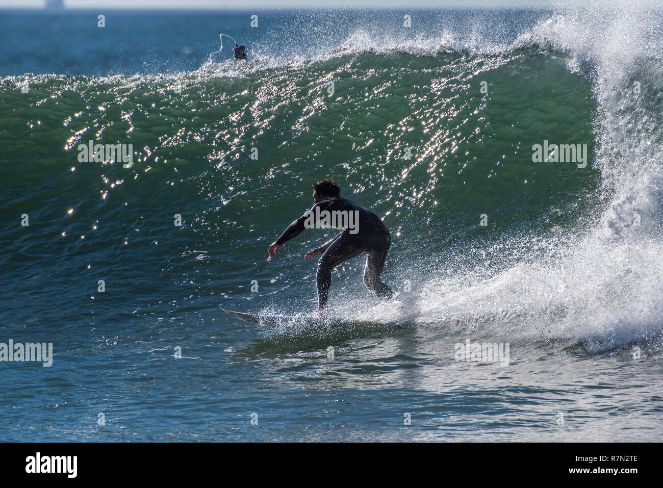 Surfer In Silhouetted Black Wetsuit Flying Across The Wave Surfer In Silhouetted Black Wetsuit Flying Across The Wave