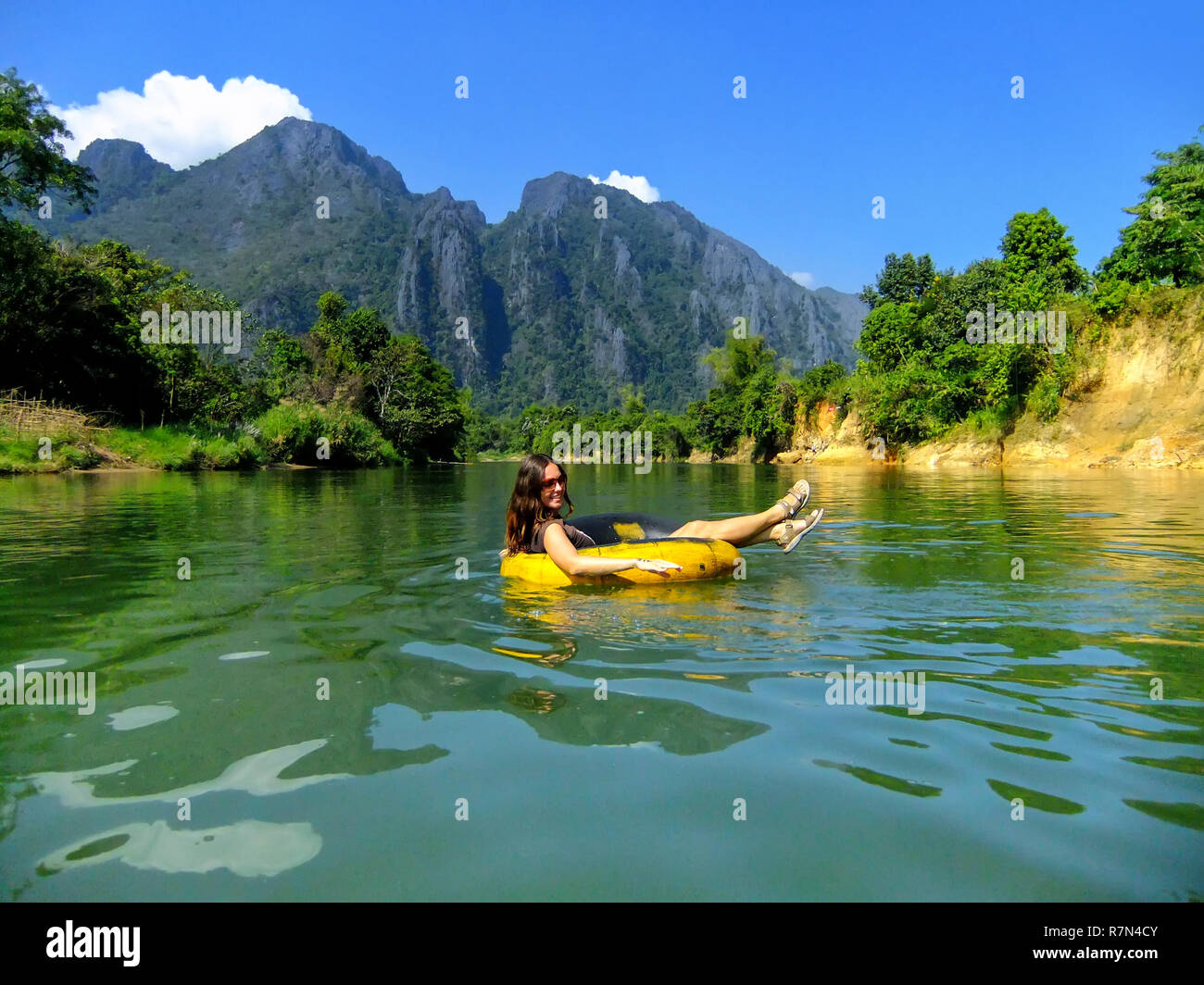 Tourist going down Nam Song River in a tube surrounded by karst scenery in Vang Vieng, Laos. Tubing is a popular tourist activity in Vang Vieng. Stock Photo