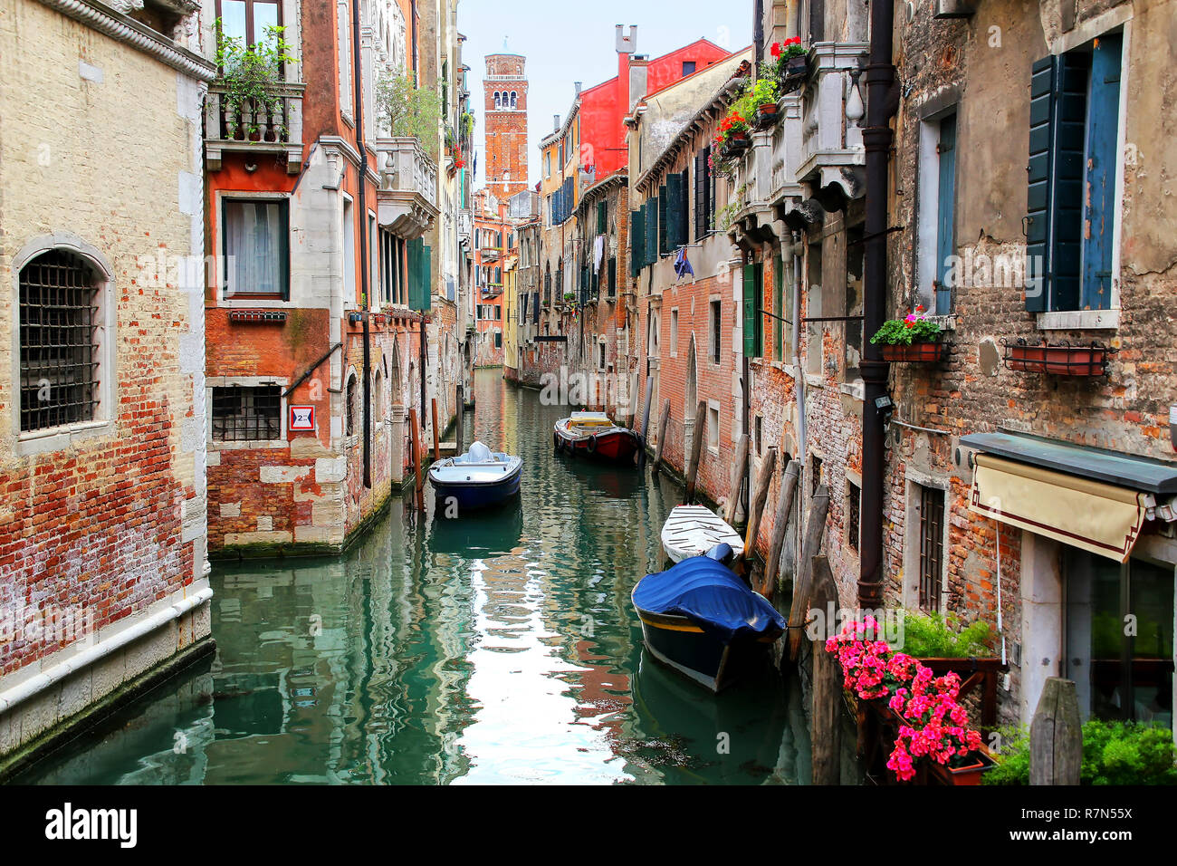 Houses and boats along narrow canal in Venice, Italy. Venice is situated across a group of 117 small islands that are separated by canals and linked b Stock Photo
