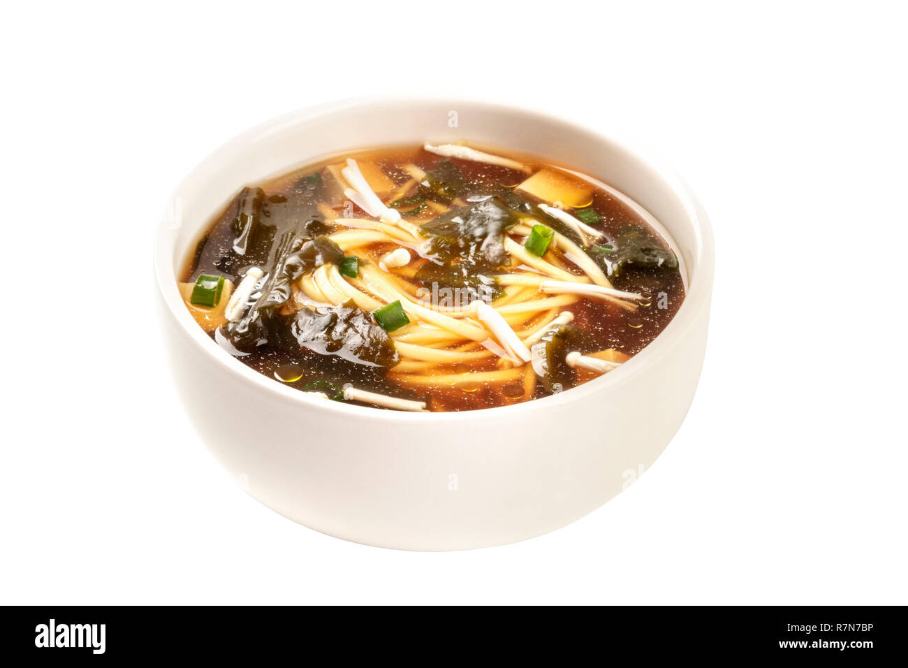 A photo of a bowl of miso soup with tofu, scallions, noodles, wakame