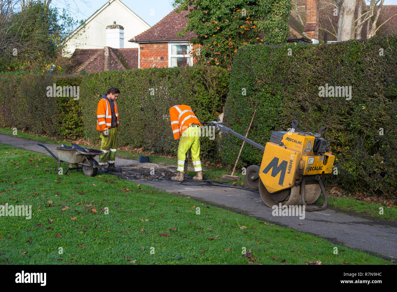 Roadside workers drilling into tarmac path, ashford, uk Stock Photo