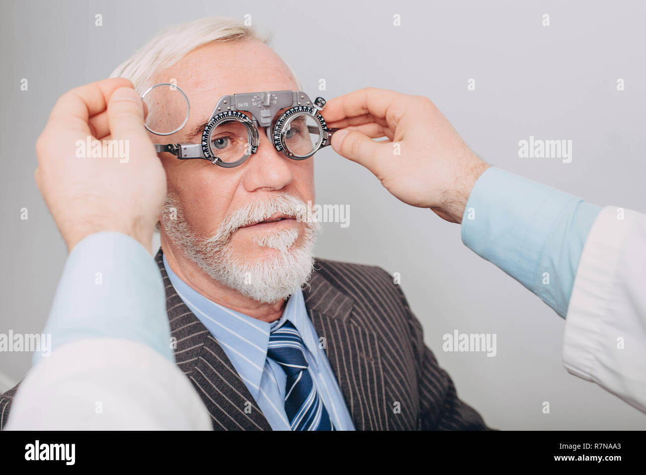 Eye doctor examining old man's vision using a trial frame Stock Photo