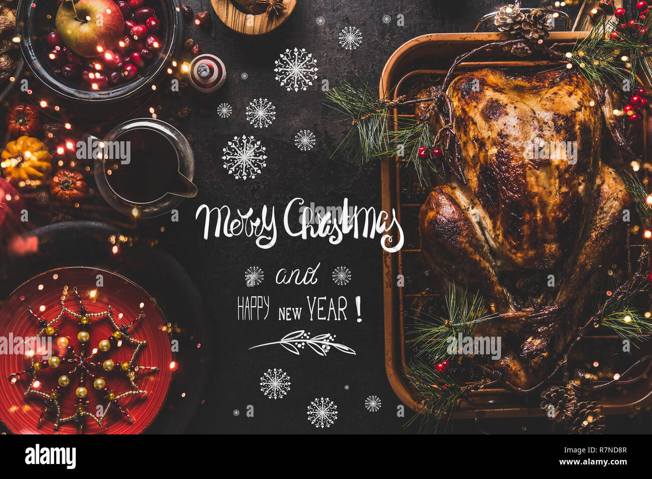Merry Christmas and Happy New Year greeting text lettering on Christmas dinner table with whole roasted turkey served with sauce, red plates, cutlery, Stock Photo