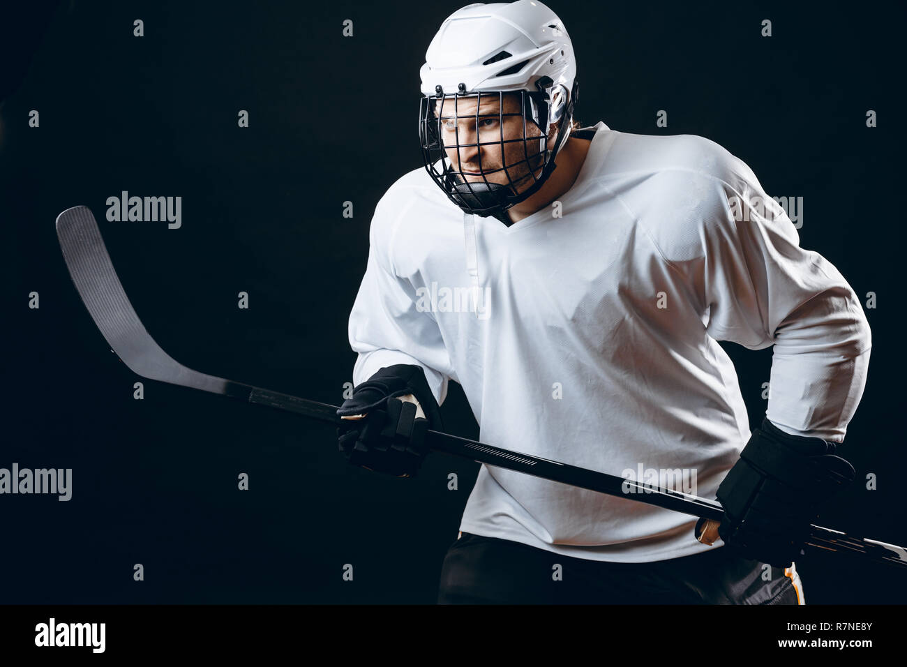 Image of icehockey player in white sportswear holding hockey stick