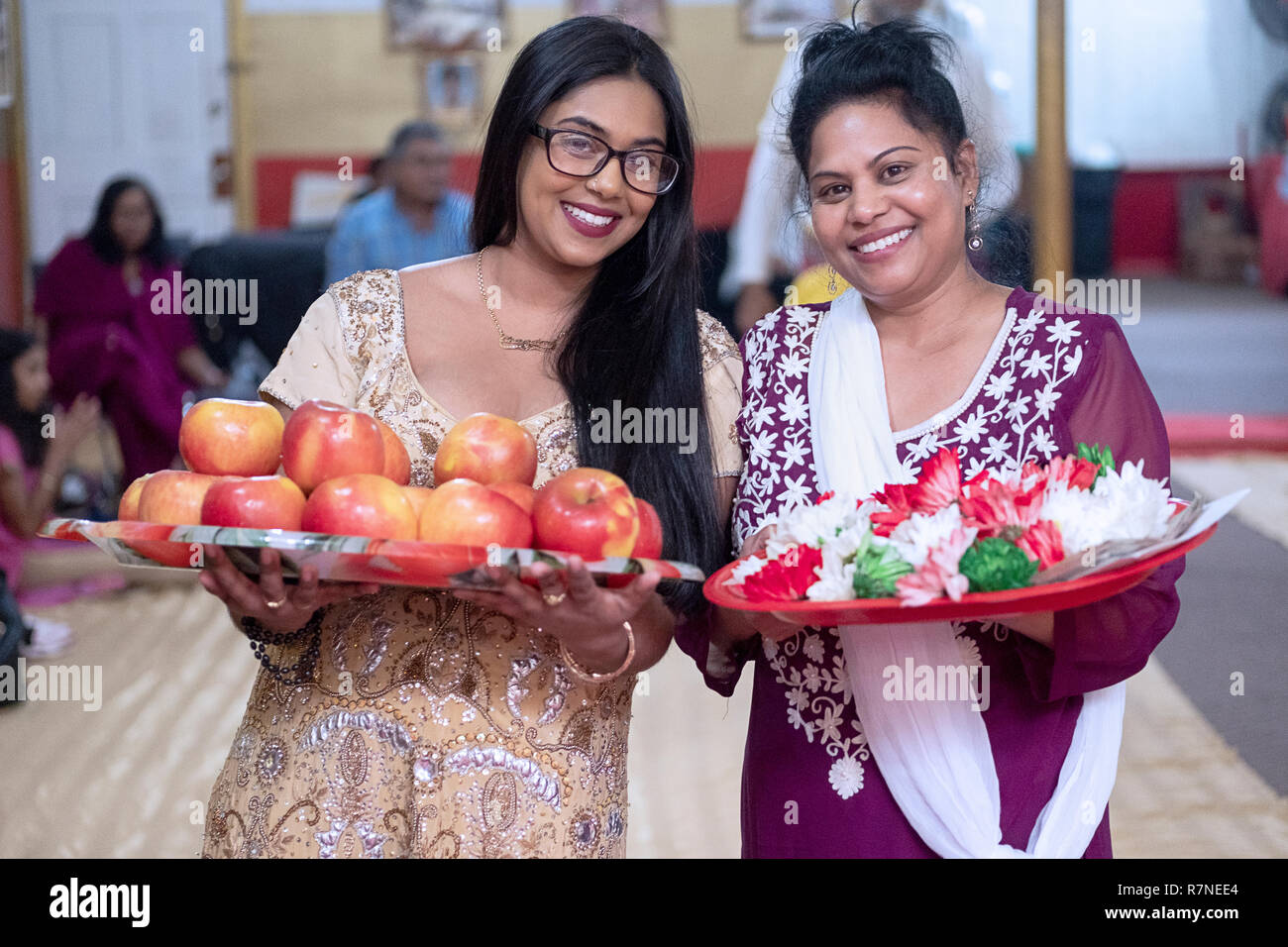 A lookalike mother and daughter pose for a photo at a Hindu temple prior to leaving offerings to the deities. In Queens, New york. Stock Photo