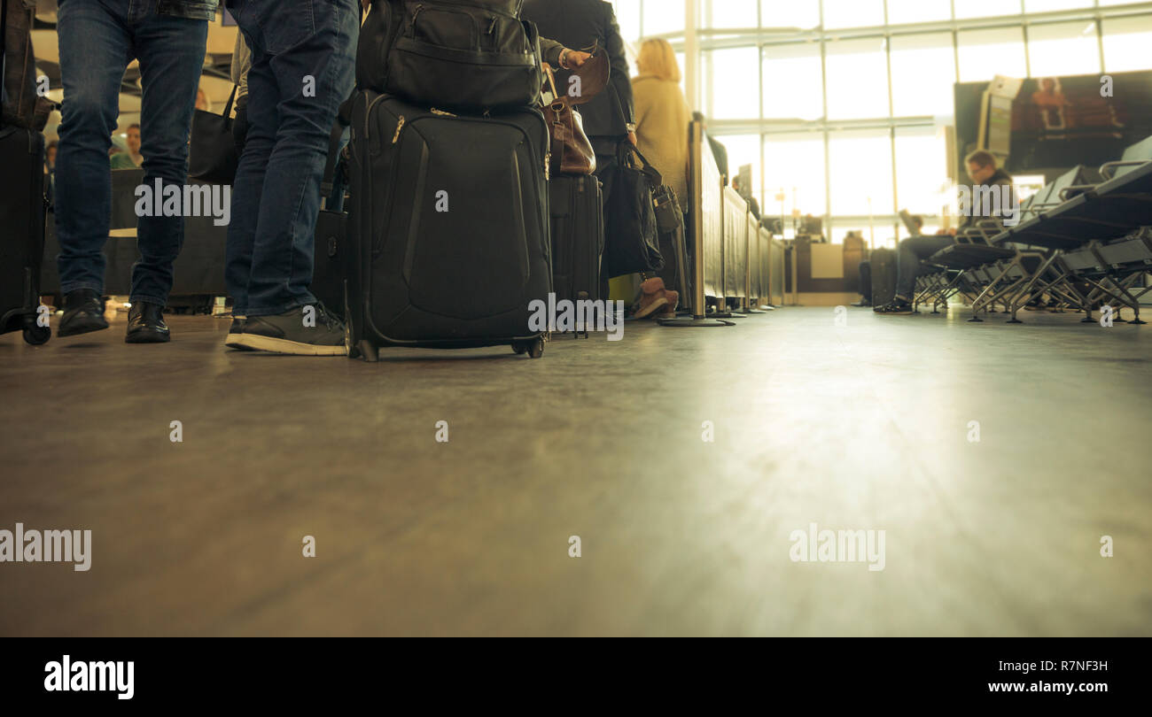 Line of people waiting to board the airplane at an airport terminal. Travellers carrying luggage Stock Photo