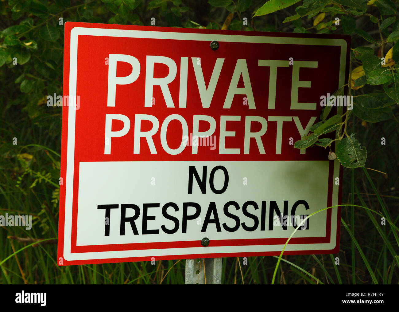 No Trespassing Private Property Sign in Green Bushes. Stock Photo