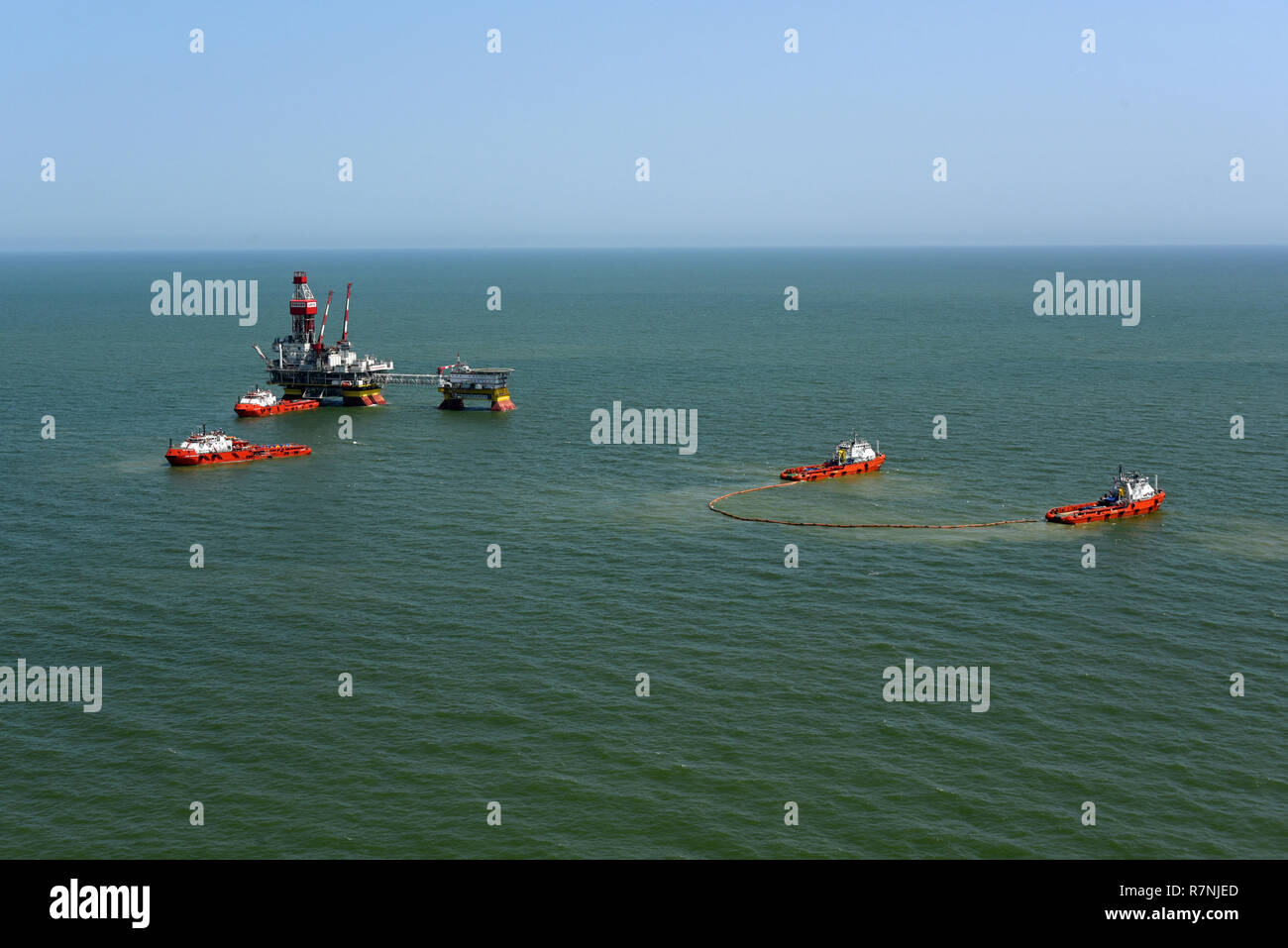 Rescue ships deploy a marine boom during the fire fighting training exercises on the oil rig Lukoil Filanovsky at the Caspian sea, Russia. Stock Photo
