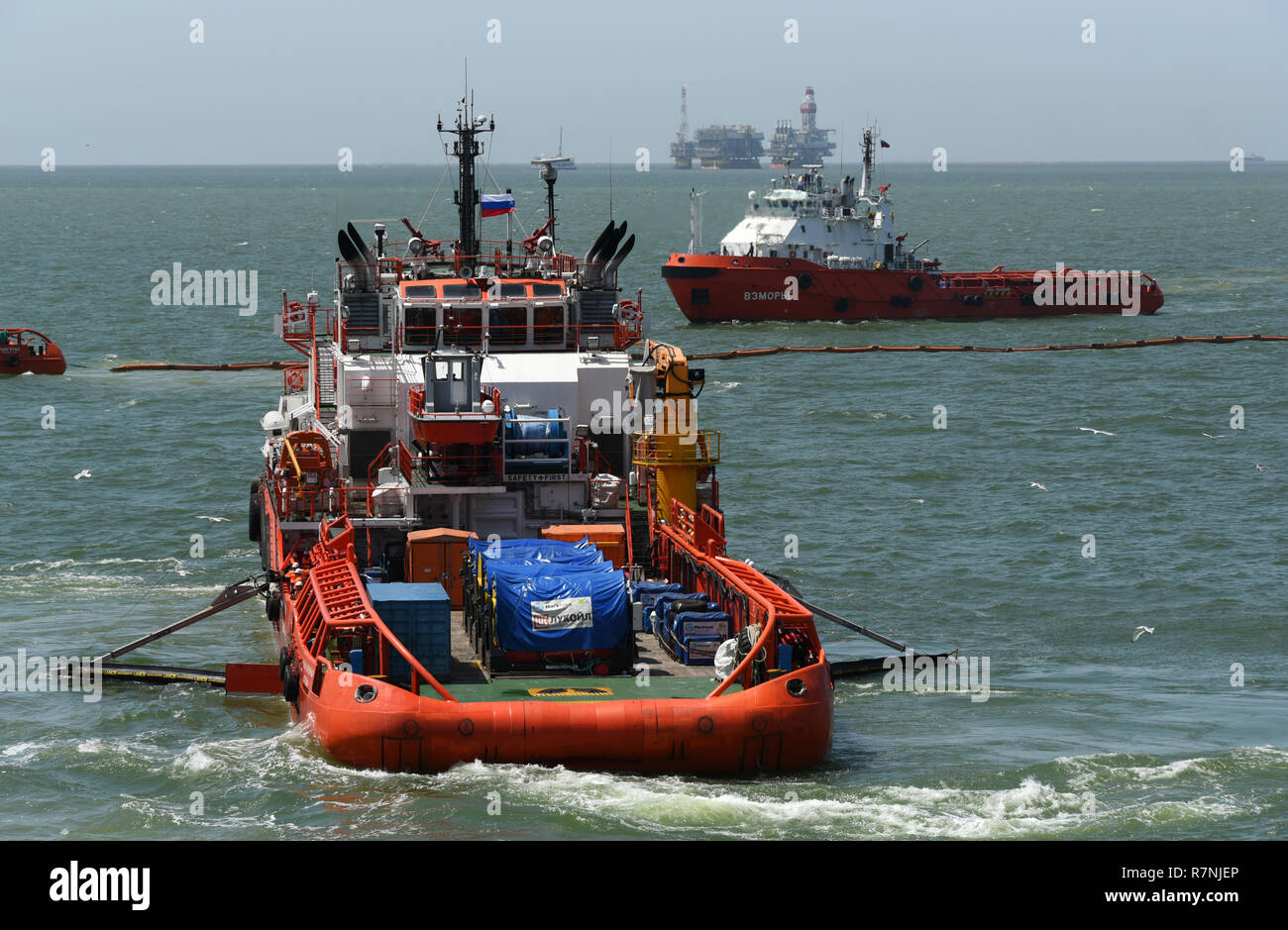 Rescue ships deploy a marine boom during the fire fighting training exercises on the oil rig Lukoil Filanovsky at the Caspian sea, Russia. Stock Photo