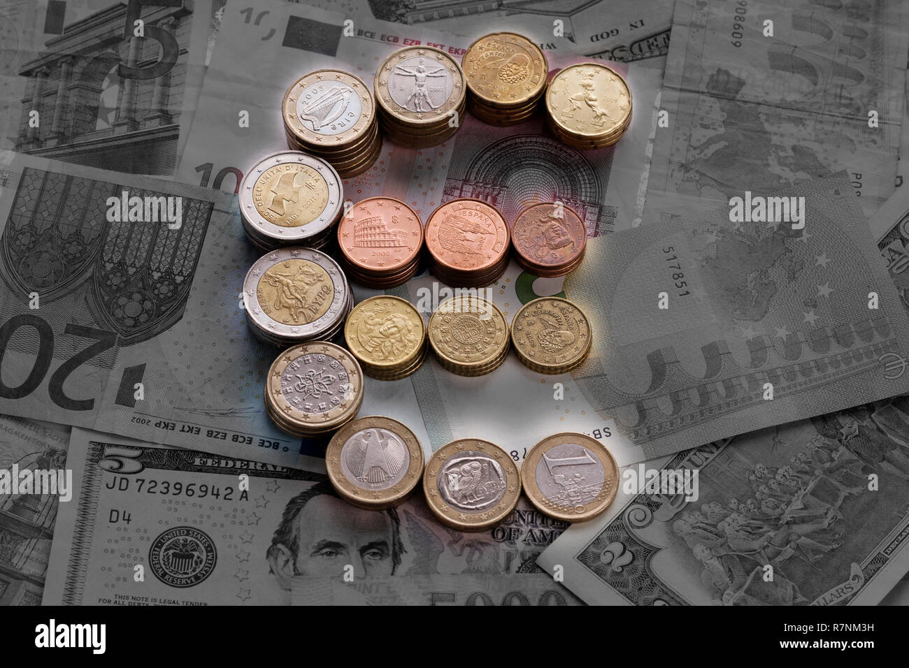 Colorful luminous euro sign from euro coins against white and black banknotes. Euro (EUR) and US dollars (USD) currency. Stock Photo