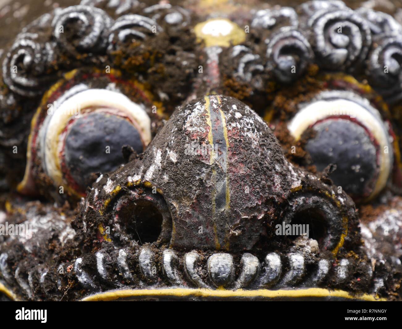 Close up of grotesque, scary face of statue of Balinese demon with staring eyes and fangs at Pura Sangara sea temple near Sanur. Stock Photo