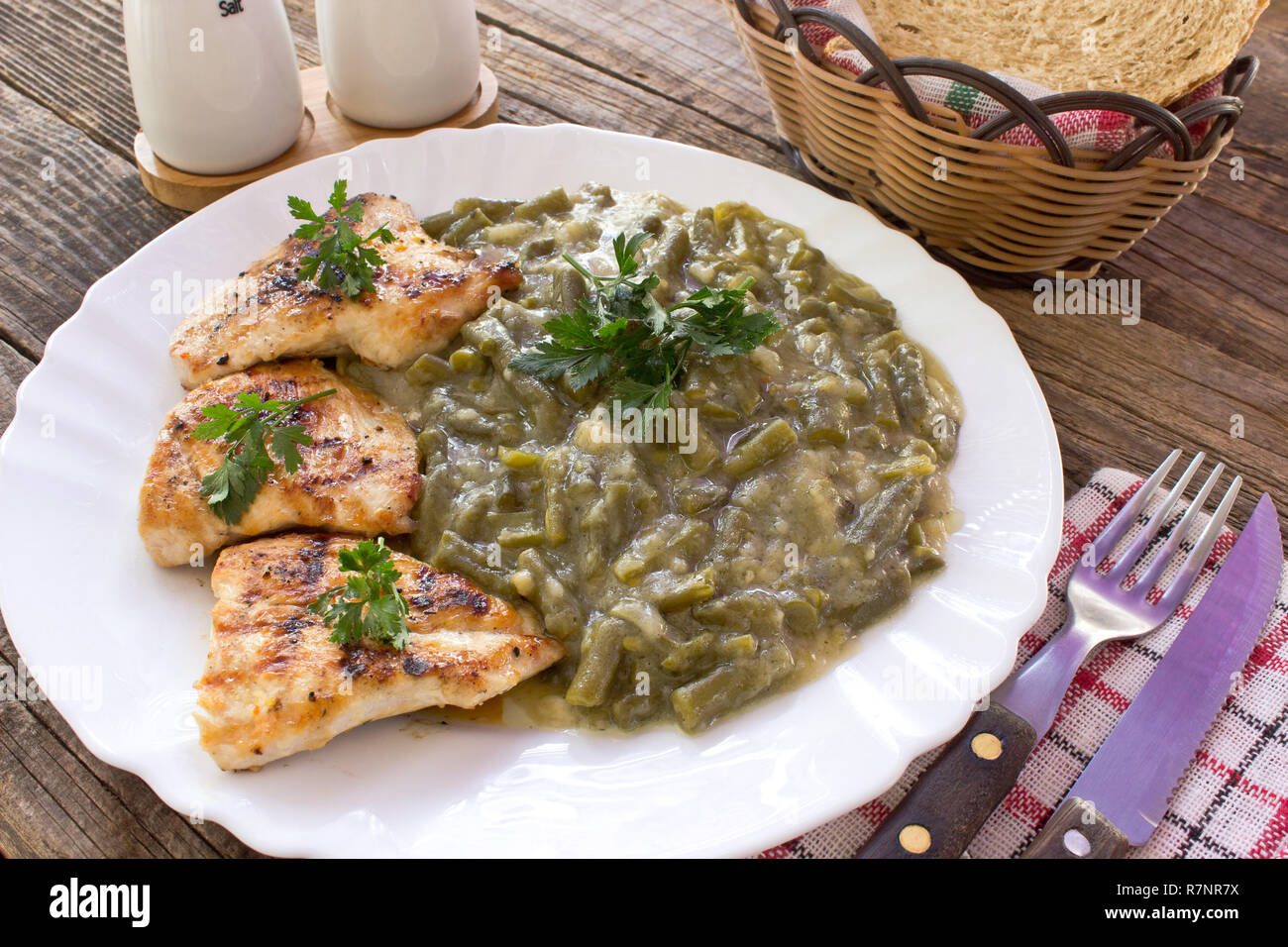 Grilled chicken breasts with cooked green beans in plate on wooden table Stock Photo