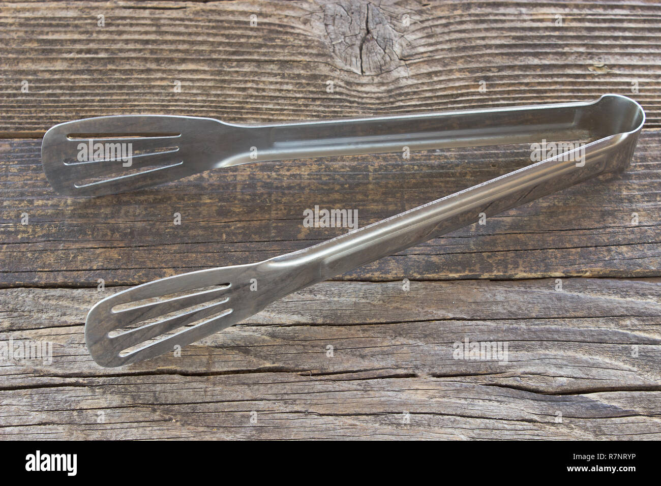 Serving tongs on wooden background Stock Photo