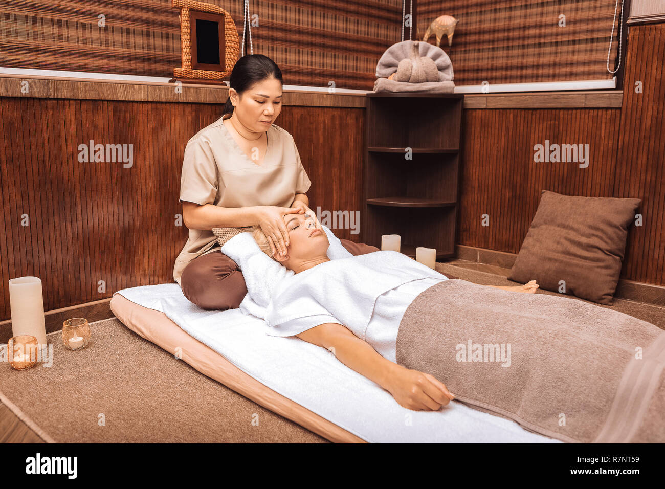 Serious Asian woman sitting near her clients head Stock Photo