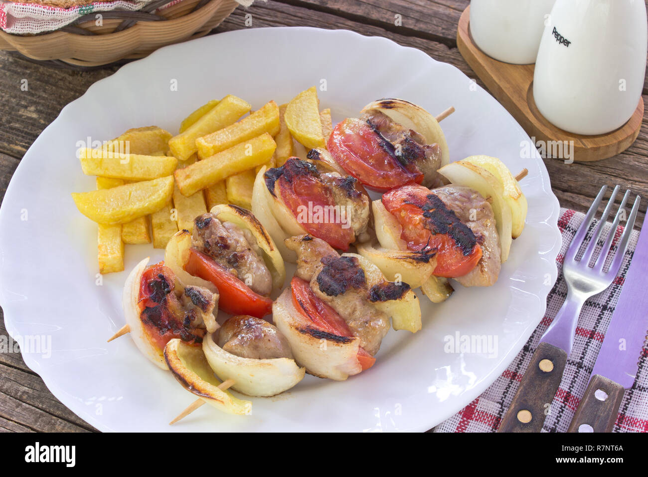 Grilled meat with vegetables on sticks in plate on table Stock Photo