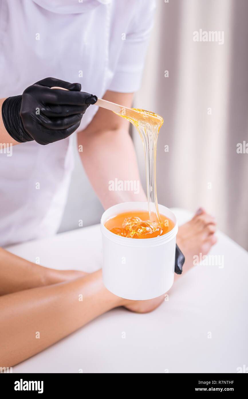 Professional depilation master removing unwanted hair from legs Stock Photo