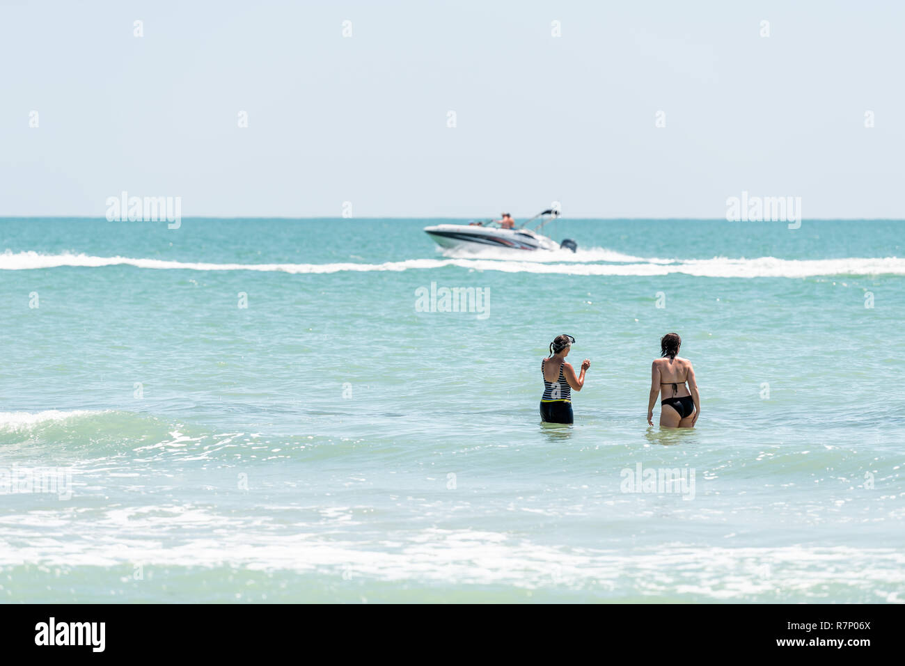 Sanibel Island, USA - April 29, 2018: Bowman's beach, Florida with one white boat yacht fishing swimming on colorful turquoise water on sunny day, wom Stock Photo