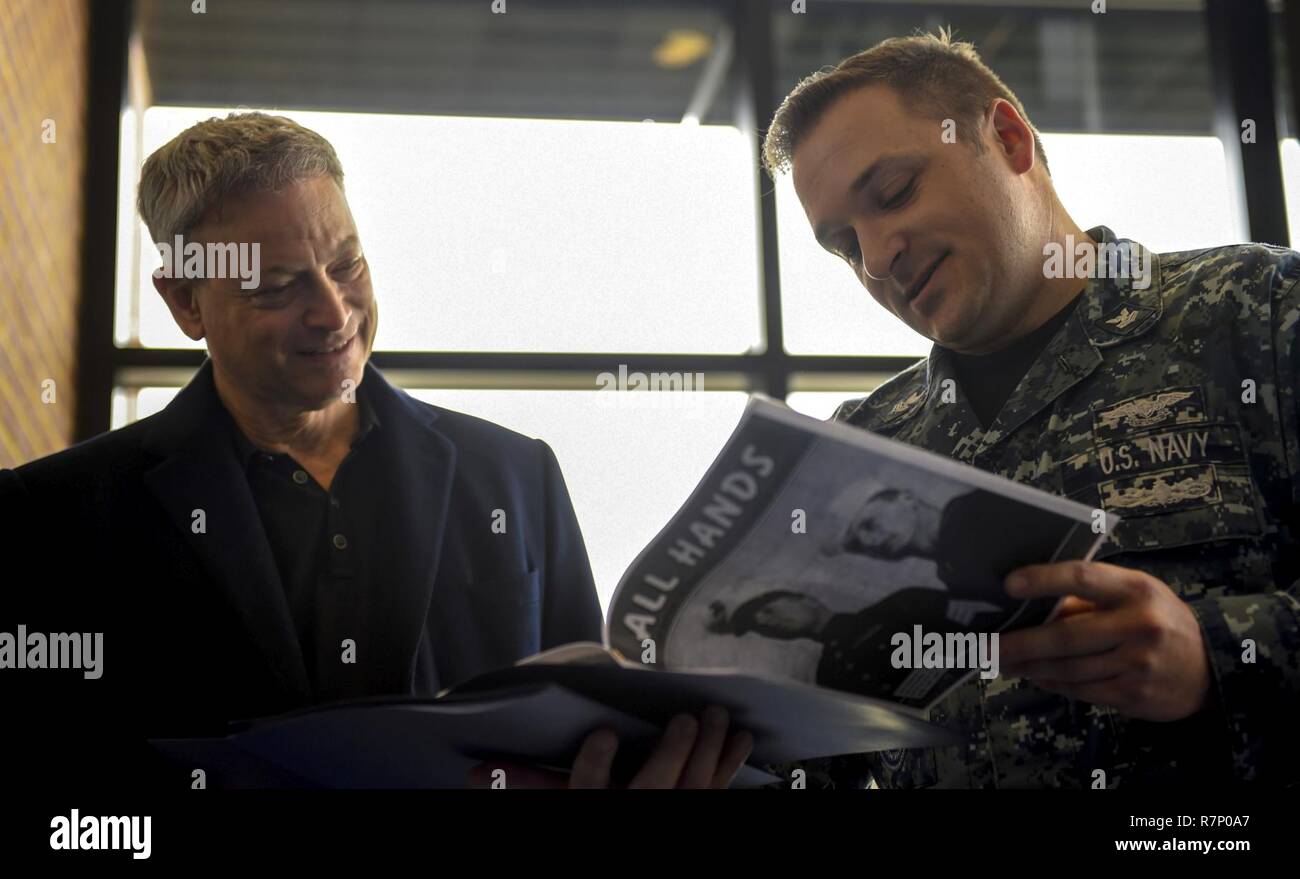 WASHINGTON (March 21, 2016) Mass Communication Specialist 1st Class Clifford L. H. Davis, assigned to the Naval History and Heritage Command, shows Criminal Minds: Beyond Borders star Gary Sinise a copy of a 1955 Navy All Hands magazine onboard Joint Base Anacostia-Bolling (JBAB). Sinise visited JBAB to see where his father, a Navy veteran photographer's mate, worked and lived before he was discharged. Stock Photo