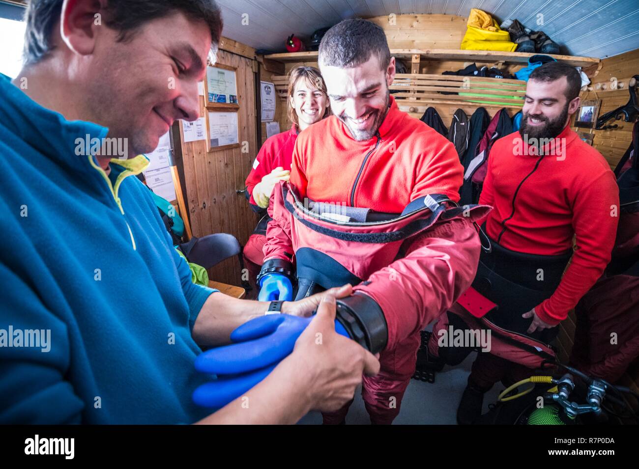 France, Isère (38), Belledonne, Chamrousse, Robert Lakes, after the pair of wool gloves to keep the hands at good temperature, an instructor screws the pair of waterproof gloves on the suit, before an ice diving - Dive Xtreme Stock Photo