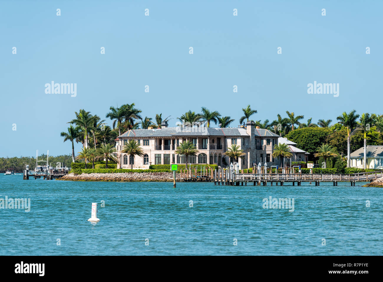 Naples, USA - April 30, 2018: Nelson's Walk houses buildings with turquoise water on Dollar bay, palm trees, blue sky in residential community, vacati Stock Photo