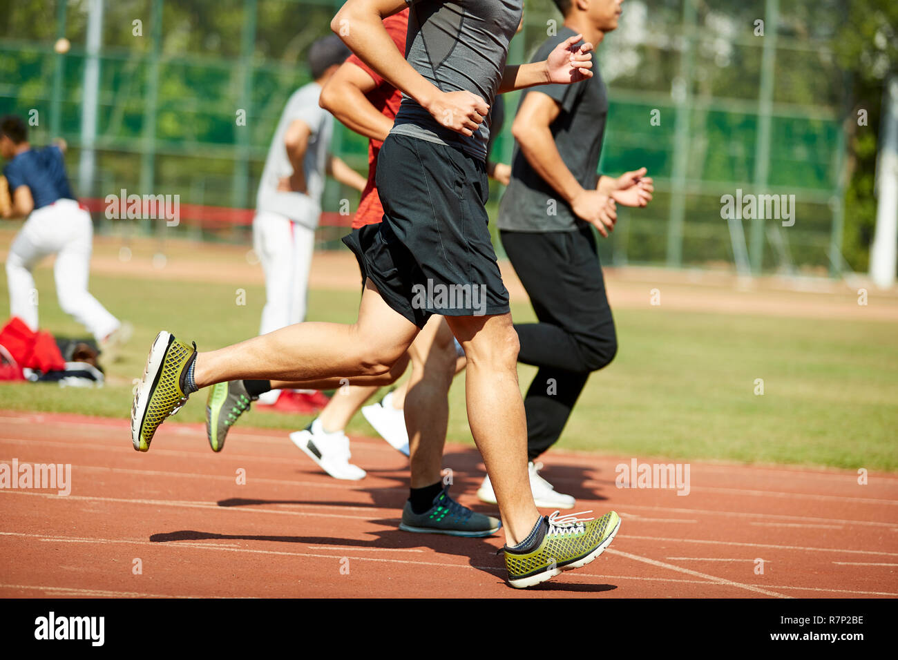 four young asian track and field athletes racing competing against each other. Stock Photo