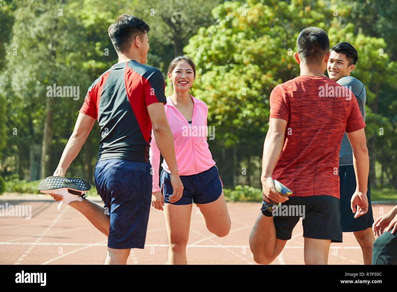 group of young asian athletes stretching legs on track getting ready for training. Stock Photo