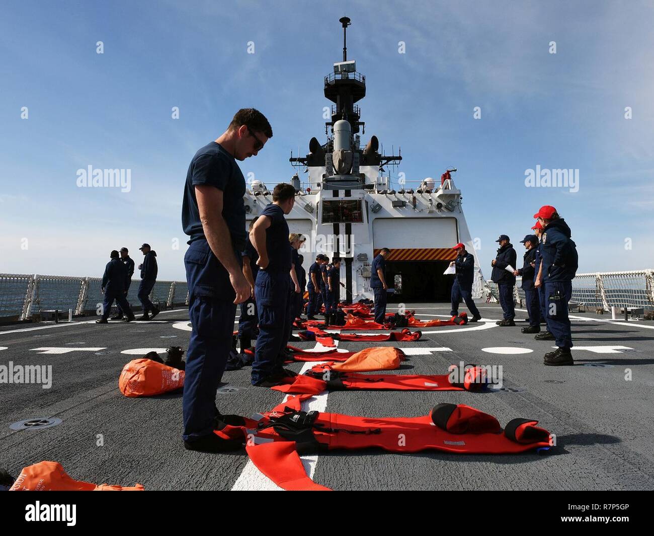 Crewmembers line up on the flight deck with their cold-water immersion or 'Gumby' suits during a cold water survival training drill aboard the Coast Guard Cutter Munro, Mar. 26, 2017. The crew had only 60 seconds to quickly and accurately put on their suits, simulating preparation for abandoning the ship in the event of an emergency. U.S. Coast Guard Stock Photo