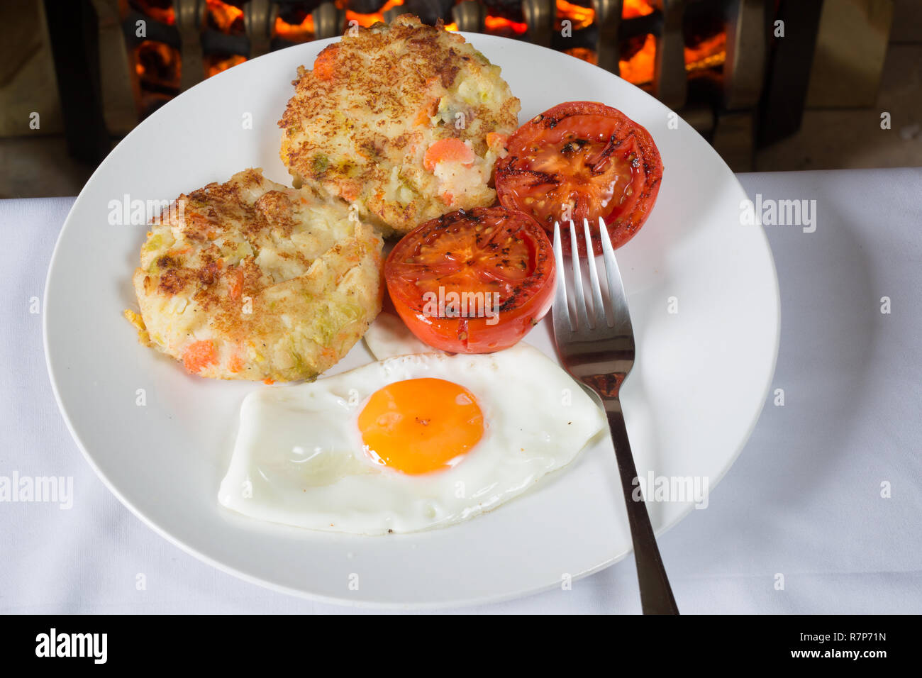 A Traditional dish of leftover Christmas dinner veg made into bubble and squeak served with fried egg and grilled Tomato Stock Photo