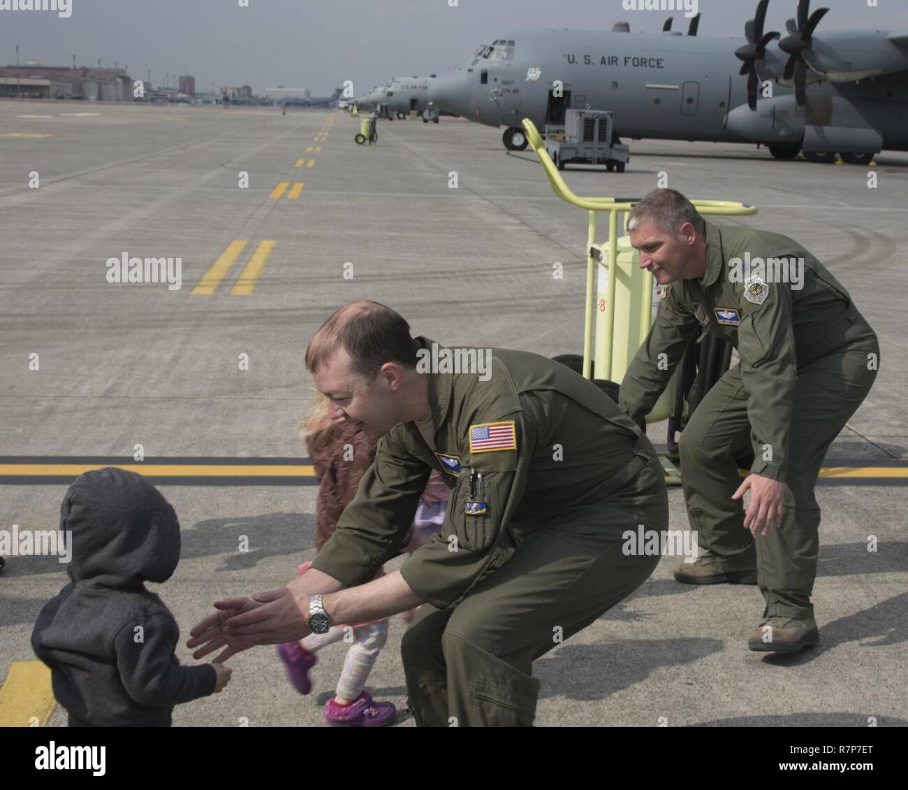 (Left to right) Tech. Sgt. Michael McArty, 374th Operations Group C-130 standardization and evaluation loadmaster, and Lt. Col. Robert Cureton, 374th Airlift Wing C-130J pilot, greet their children after landing at Yokota Air Base, Japan, March 29, 2017. This is the second C-130J delivered from Lockheed Martin, less than a month after the first was delivered March 6th. Stock Photo