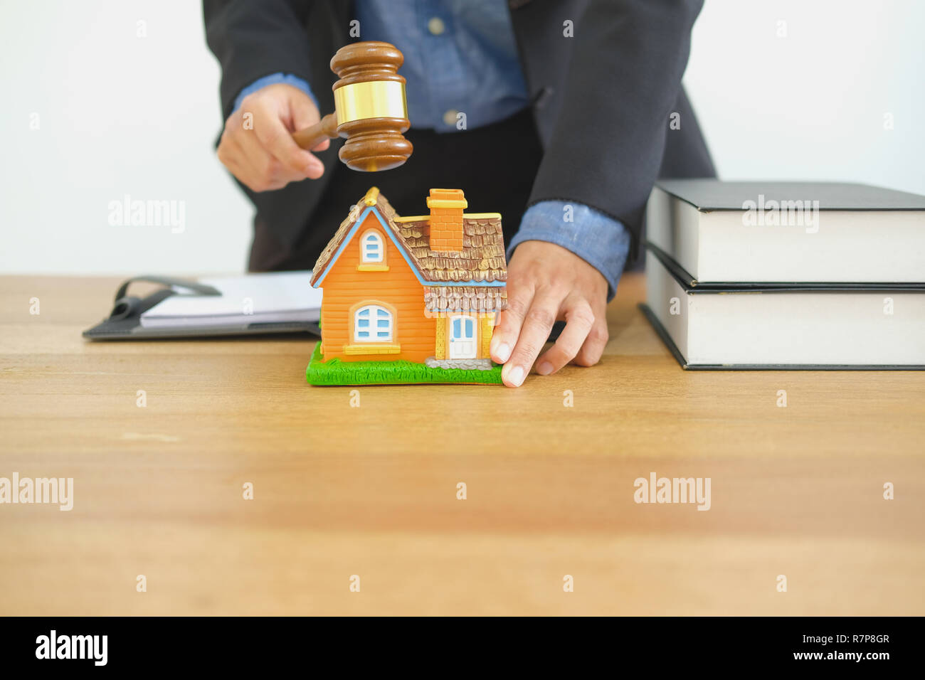 lawyer with judge gavel knocking house model at courtroom. real estate dispute & property auction concept Stock Photo
