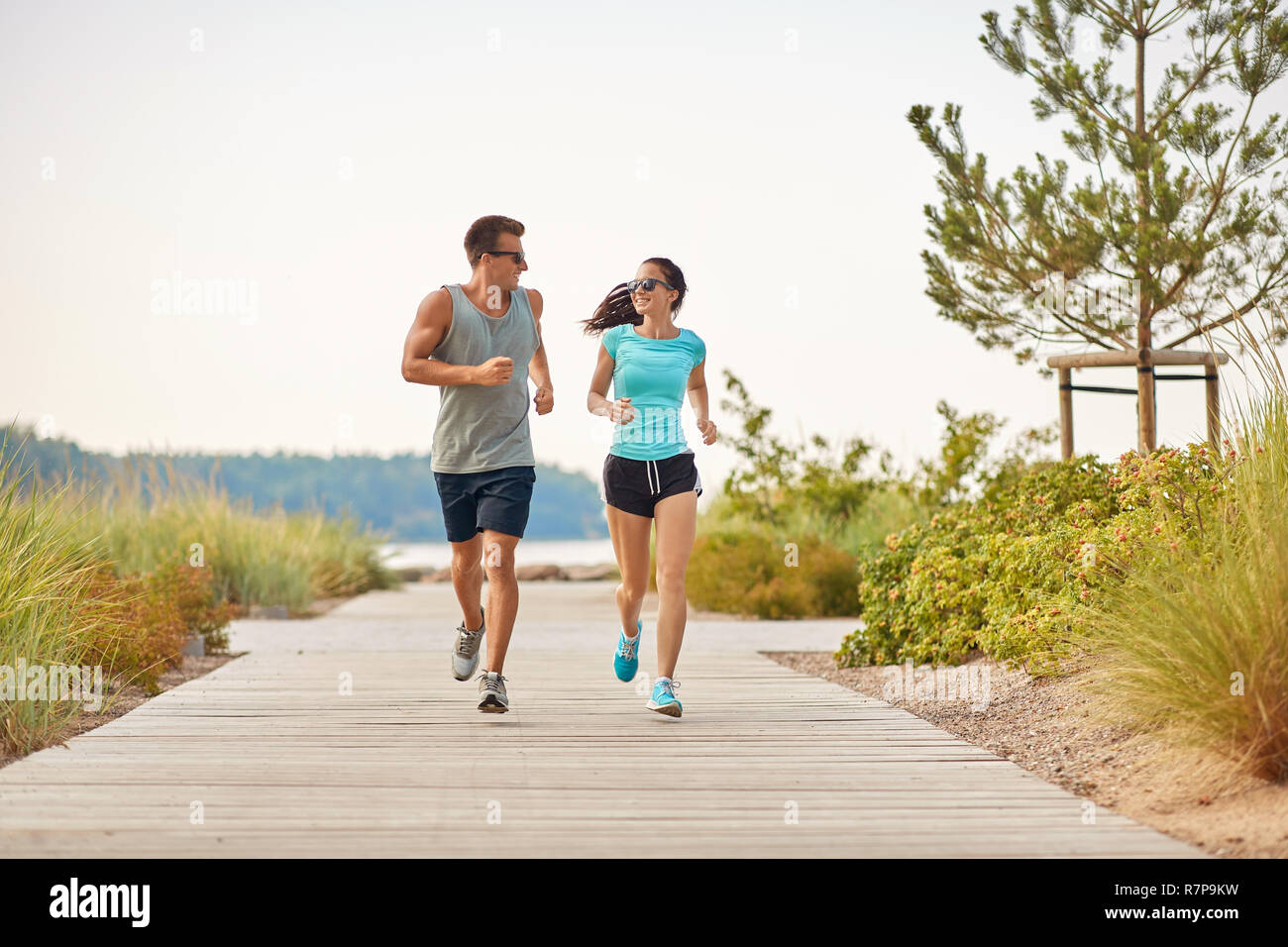 couple in sports clothes running along beach path Stock Photo - Alamy