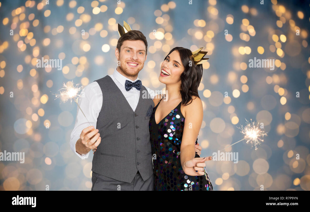 happy couple with crowns and sparklers at party Stock Photo