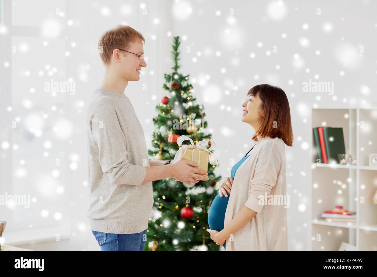 husband giving christmas present to pregnant wife Stock Photo - Alamy