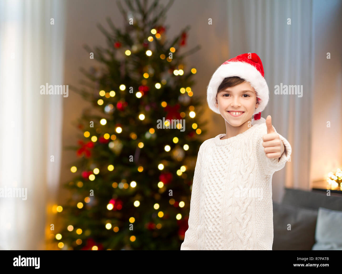 happy boy in santa hat showing thumbs up Stock Photo