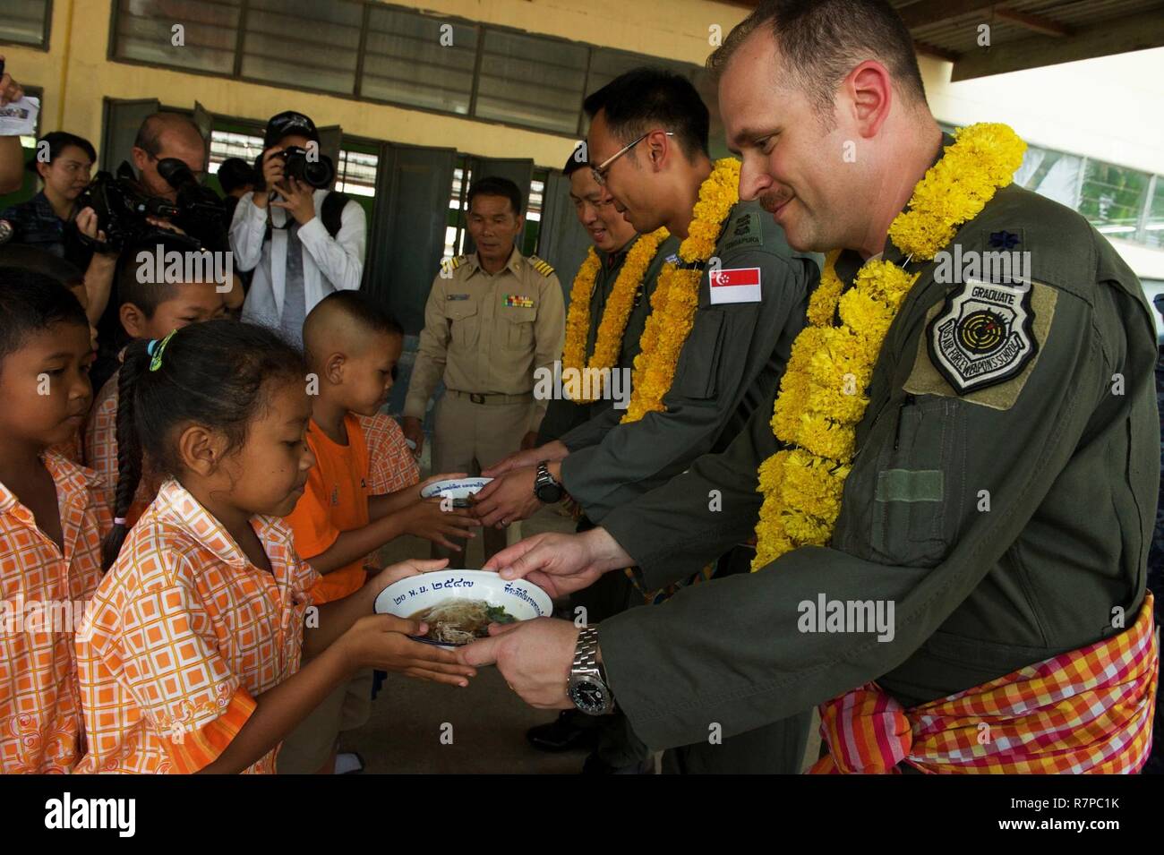 U.S. Air Force Lt. Col. James McFarland, exercise director for Cope Tiger 17 (CT17), along with the Republic of Singapore air force and Royal Thai air force exercise directors participate in lunch service for students of Ban Tanod Poonpol Witthaya School, Nakhon Ratchasima Province, during a combined civic action engagement in Thailand, March 22, 2017. The combined civic action engagement provides an outlet for the countries participating in CT17 to give back to the community surrounding Korat Royal Thai Air Force Base. Over 1,200 U.S., Thai and Singaporean military members will participate in Stock Photo