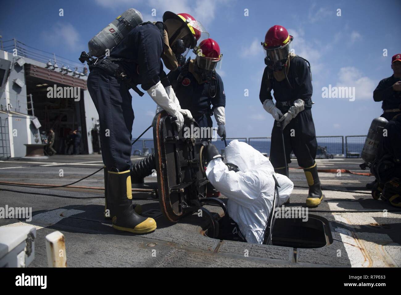 SOUTH CHINA SEA (March 20, 2017) Hull Maintenance Technician Fireman Adam Welkovich, from Stamford, Connecticut, climbs down a scuttle on the flight deck during a toxic gas drill aboard Arleigh Burke-class guided-missile destroyer USS Michael Murphy (DDG 112). Michael Murphy is on a regularly scheduled Western Pacific deployment with the Carl Vinson Carrier Strike Group as part of the U.S. Pacific Fleet-led initiative to extend the command and control functions of U.S. 3rd Fleet. U.S. Navy aircraft carrier strike groups have patrolled the Indo-Asia-Pacific regularly and routinely for more than Stock Photo