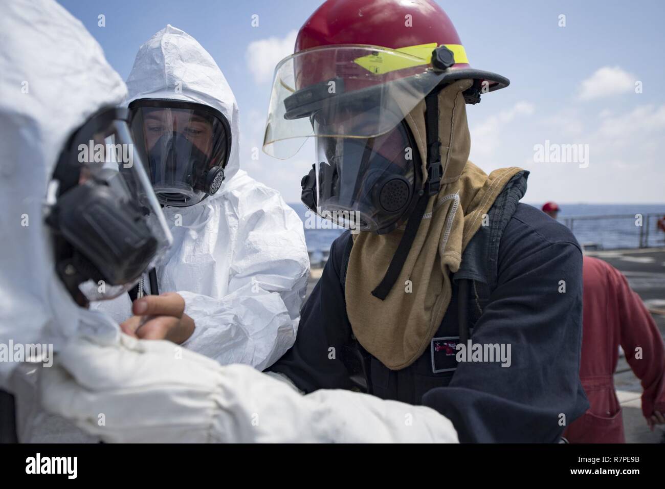SOUTH CHINA SEA (March 20, 2017) Sailors help each other don protective gear during a toxic gas drill aboard Arleigh Burke-class guided-missile destroyer USS Michael Murphy (DDG 112). Michael Murphy is on a regularly scheduled Western Pacific deployment with the Carl Vinson Carrier Strike Group as part of the U.S. Pacific Fleet-led initiative to extend the command and control functions of U.S. 3rd Fleet. U.S. Navy aircraft carrier strike groups have patrolled the Indo-Asia-Pacific regularly and routinely for more than 70 years. Stock Photo