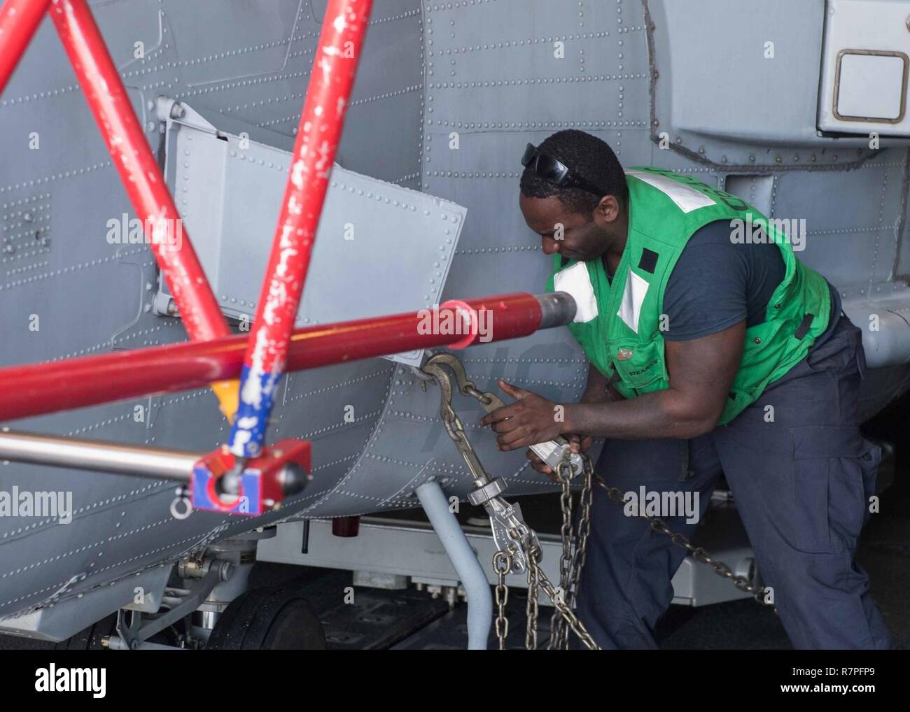 PACIFIC OCEAN (March 23, 2017) Aviation Electronics Technician 3rd Class Melshi Miclisse, from Palm Bay, Fla., chains down an MH-60R Sea Hawk helicopter assigned to the 'Scorpions' of Helicopter Maritime Strike Squadron (HSM) 49 in the hangar bay aboard the Ticonderoga-class guided-missile cruiser USS Lake Erie (CG 70) while underway conducting a composite training unit exercise (COMPTUEX) with the Nimitz Carrier Strike Group in preparation for an upcoming deployment. COMPTUEX tests the mission-readiness of the strike group's assets through simulated real-world scenarios and their ability to p Stock Photo