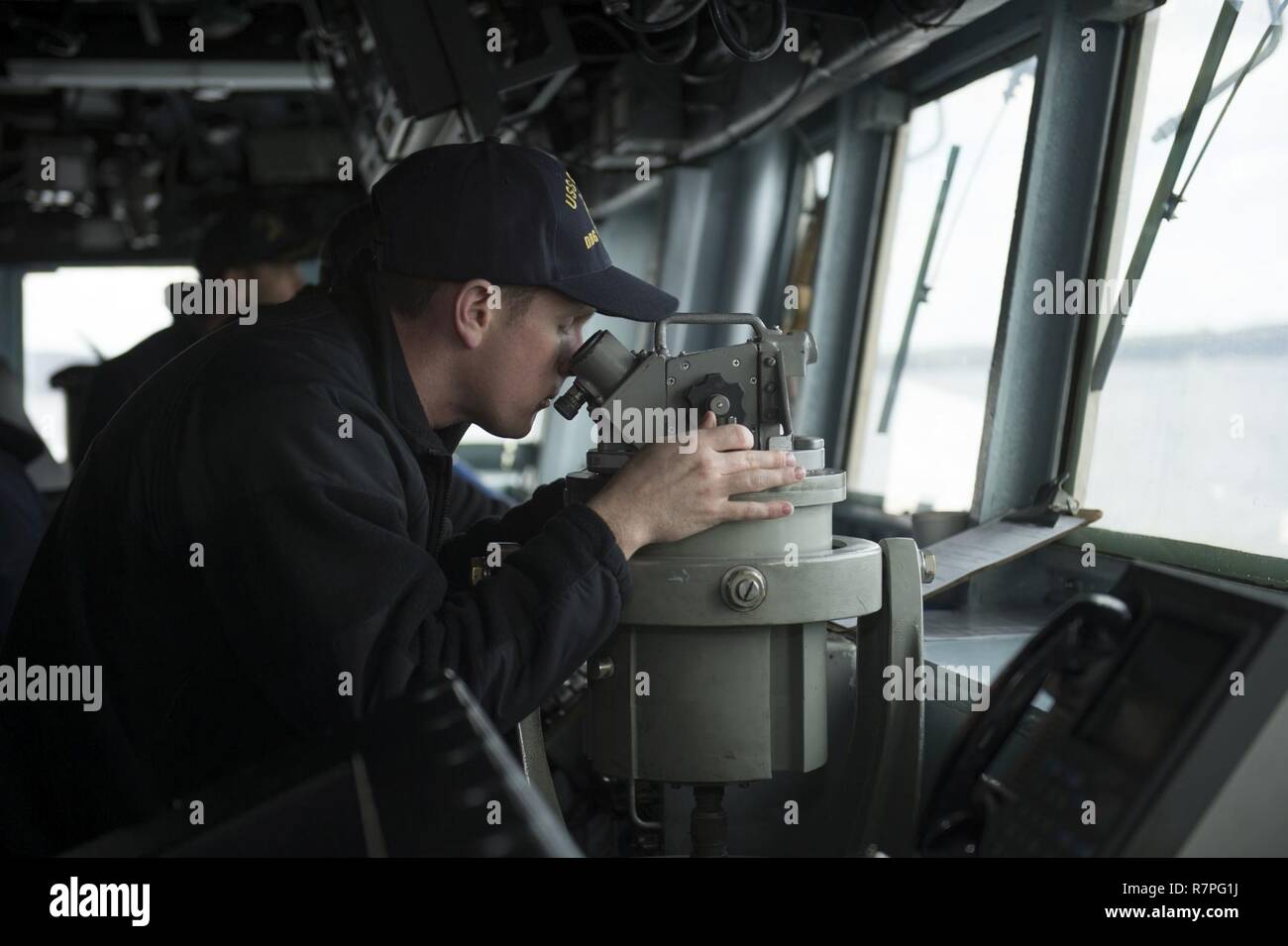 FASLANE, Scotland (March 22, 2017) Ensign Logan O'Shea looks through a telescopic alidade aboard the guided-missile destroyer USS Carney (DDG 64) while pulling into Faslane, Scotland, for a scheduled port visit. Carney is forward-deployed to Rota, Spain, and is conducting its third patrol in the U.S. 6th Fleet area of operations in support of U.S. national security interests in Europe. Stock Photo