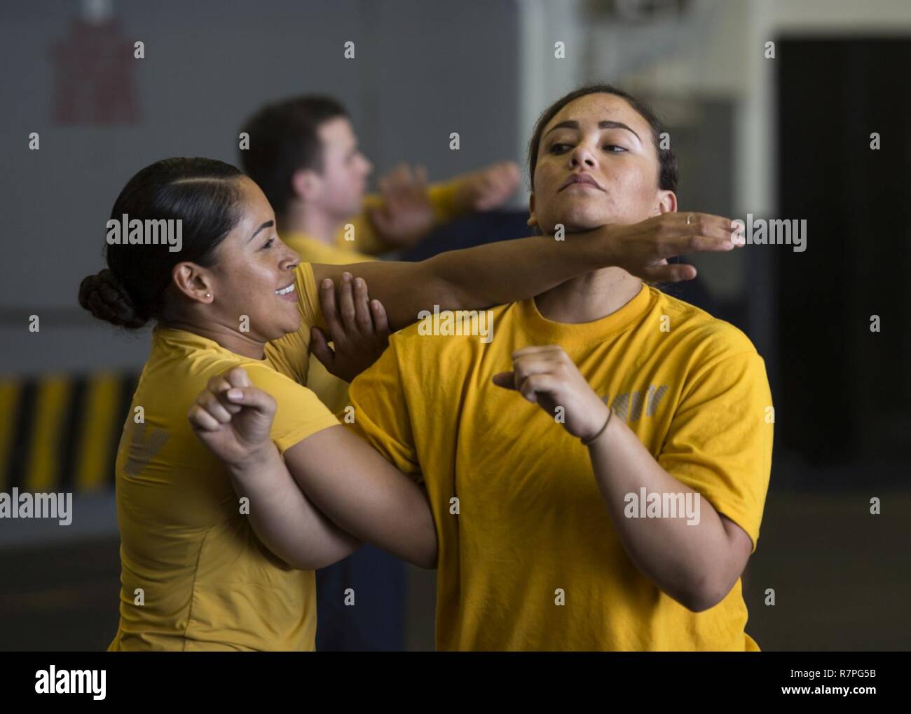 ARABIAN SEA (March 22, 2017) Aviation Machinist’s Mate 2nd Class Amelia Grubbs, from Belize, Calif., left, and Aviation Boatswain’s Mate (Handling) Airman Jennifer Lebron, from Guayama, Puerto Rico, practice takedowns during naval security force sentry training in the hangar bay of the amphibious assault ship USS Makin Island (LHD 8). Makin Island is deployed in the U.S. 5th Fleet area of operations in support of maritime security operations designed to reassure allies and partners, and preserve the freedom of navigation and the free flow of commerce in the region. Stock Photo