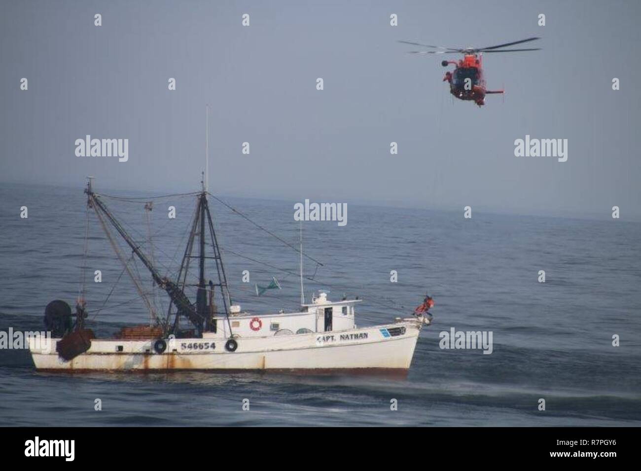 A helicopter from Air Station Atlantic City in Egg Harbor Township, NJ, hovers close to the Capt Nathan trawler 50 miles east of Chincoteague, Virginia, Sunday, March 26, 2017. The Coast Guard medevaced the captain of the trawler after it was reported he was suffering stroke-like symptons. Stock Photo