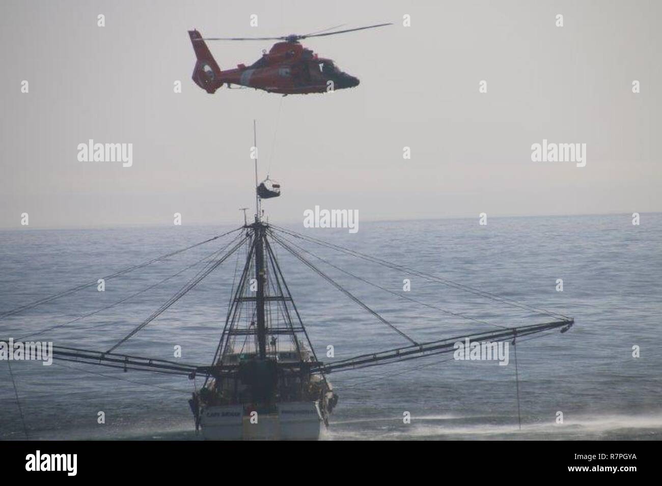 A helicopter from Air Station Atlantic City in Egg Harbor Township, NJ, hovers close to the Capt Nathan trawler 50 miles east of Chincoteague, Virginia, Sunday, March 26, 2017. The Coast Guard medevaced the captain of the trawler after it was reported he was suffering stroke-like symptons. Stock Photo