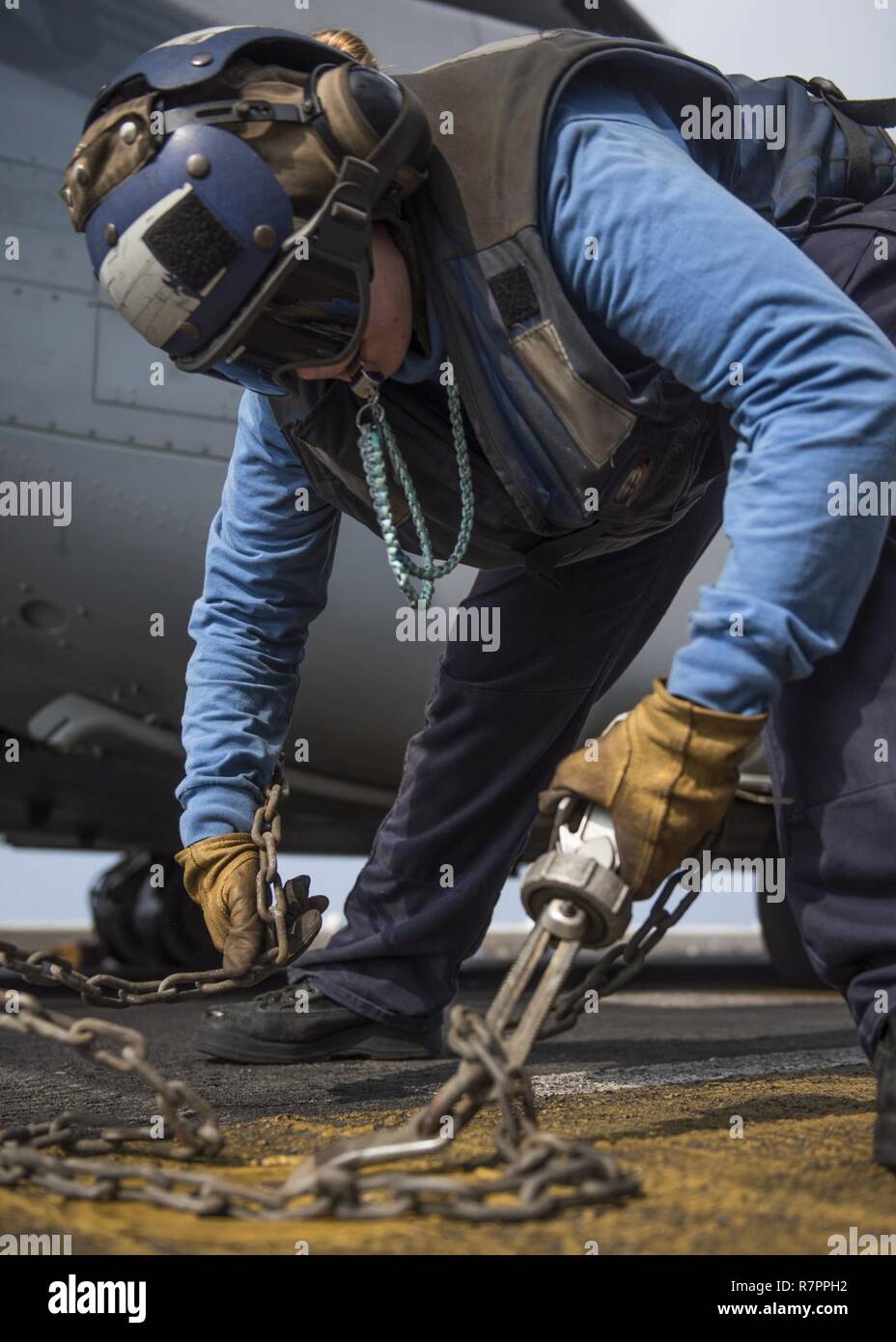 INDIAN OCEAN (March 27, 2017) Airman Christina Kozierowski, from Huntsville, Alabama, attaches a tie-down chain to a pad eye to secure an MV-22B Osprey, assigned to the Ridge Runners of Marine Medium Tiltrotor Squadron (VMM) 163, on the flight deck of the amphibious assault ship USS Makin Island (LHD 8). The ship and its amphibious ready group, with the embarked 11th Marine Expeditionary Unit, are operating in the Indo-Asia-Pacific region to enhance amphibious capability with regional partners and to serve as a ready-response force for any type of contingency. Stock Photo