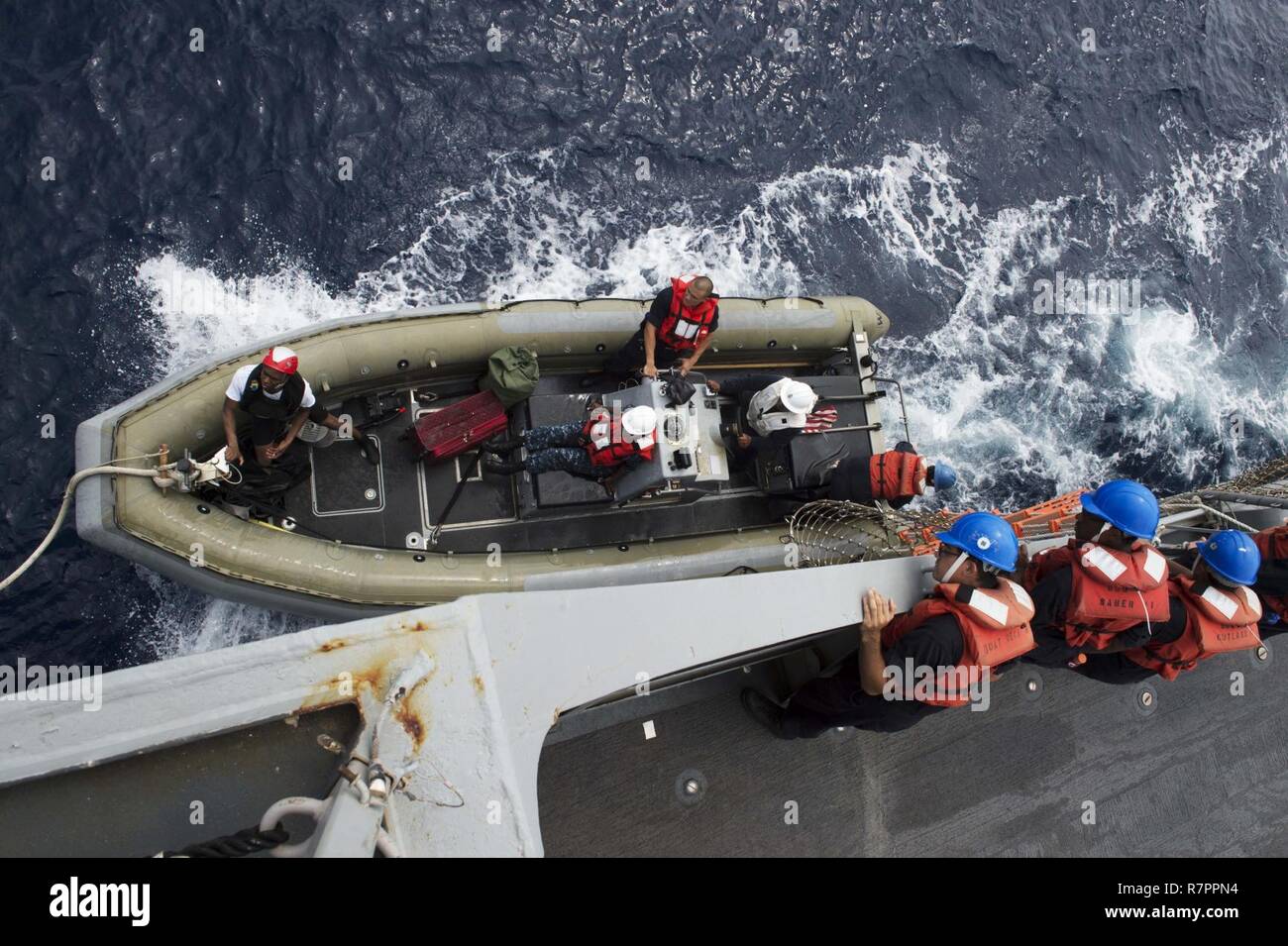 SOUTH CHINA SEA (March 23, 2017) Crew members of the forward-deployed Arleigh Burke-class guided-missile destroyer USS Fitzgerald (DDG 62) lower a rigid hull inflatable boat (RHIB) to conduct a transfer of personnel while underway. Fitzgerald is in the U.S. 7th Fleet area of operations supporting security and stability in the Indo-Asia-Pacific region. Stock Photo