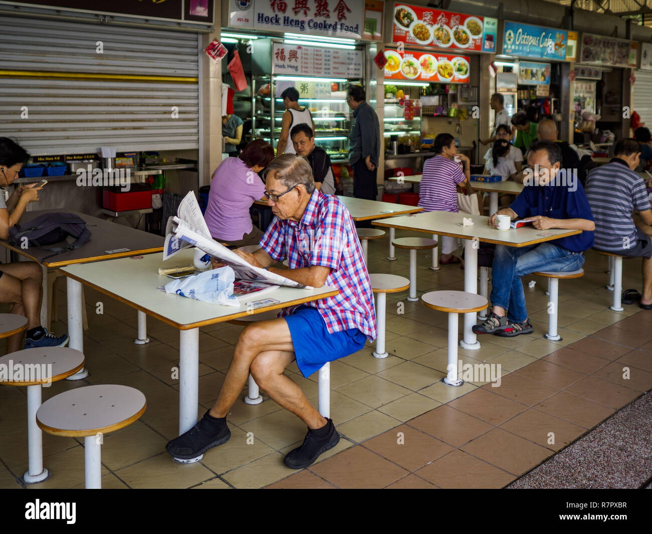 Singapore Singapore 11th Dec 2018 A Man Reads His Newspaper In A Hawker Court At The Haig Road Market And Food Centre In The Geylang Neighborhood The Geylang Area Of Singapore Between