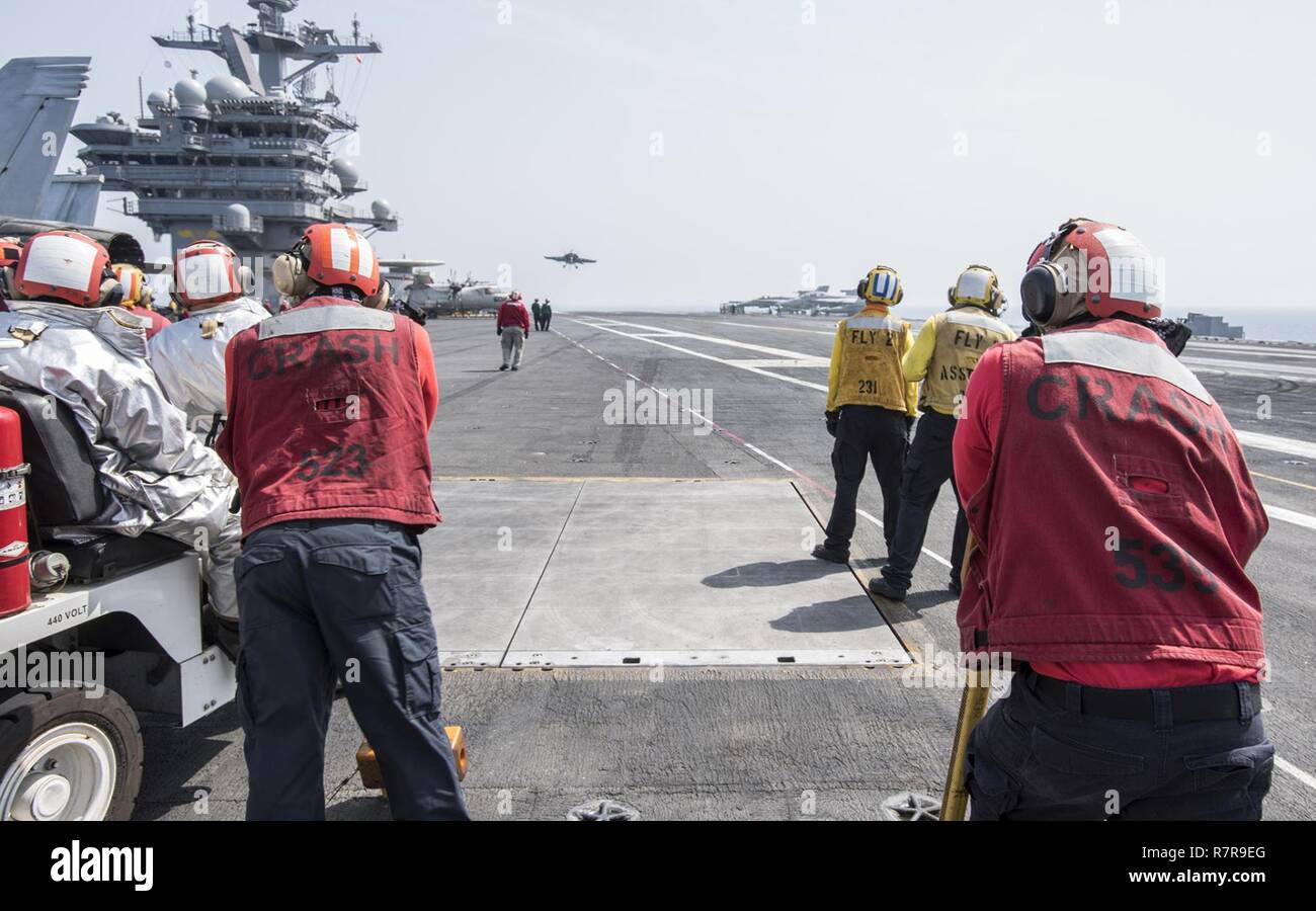 ARABIAN GULF (March 27, 2017) Sailors watch as an F/A-18E Super Hornet attached to the 'Golden Warriors' of Strike Fighter Squadron (VFA) 87 prepares to land on the flight deck of the aircraft carrier USS George H.W. Bush (CVN 77) (GHWB). GHWB is deployed in the U.S. 5th Fleet area of operations in support of maritime security operations designed to reassure allies and partners, and preserve the freedom of navigation and the free flow of commerce in the region. Stock Photo