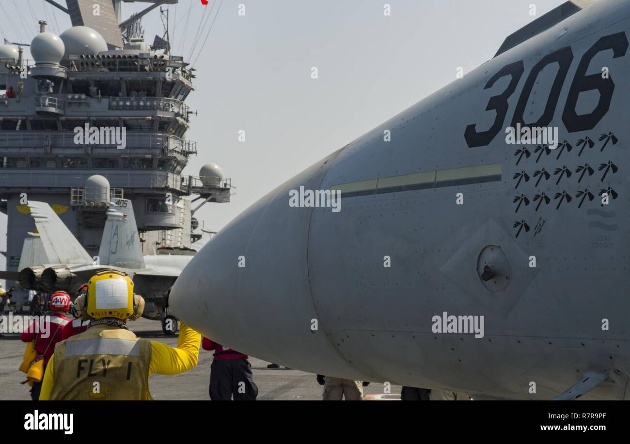 ARABIAN GULF (March 27, 2017) Aviation Boatswain's Mate (Handling) Joshua Colo stands near an F/A-18E Super Hornet attached to the 'Golden Warriors' of Strike Fighter Squadron (VFA) 87 on the flight deck of the aircraft carrier USS George H.W. Bush (CVN 77) (GHWB). GHWB is deployed in the U.S. 5th Fleet area of operations in support of maritime security operations designed to reassure allies and partners, and preserve the freedom of navigation an the free flow of commerce in the region. Stock Photo