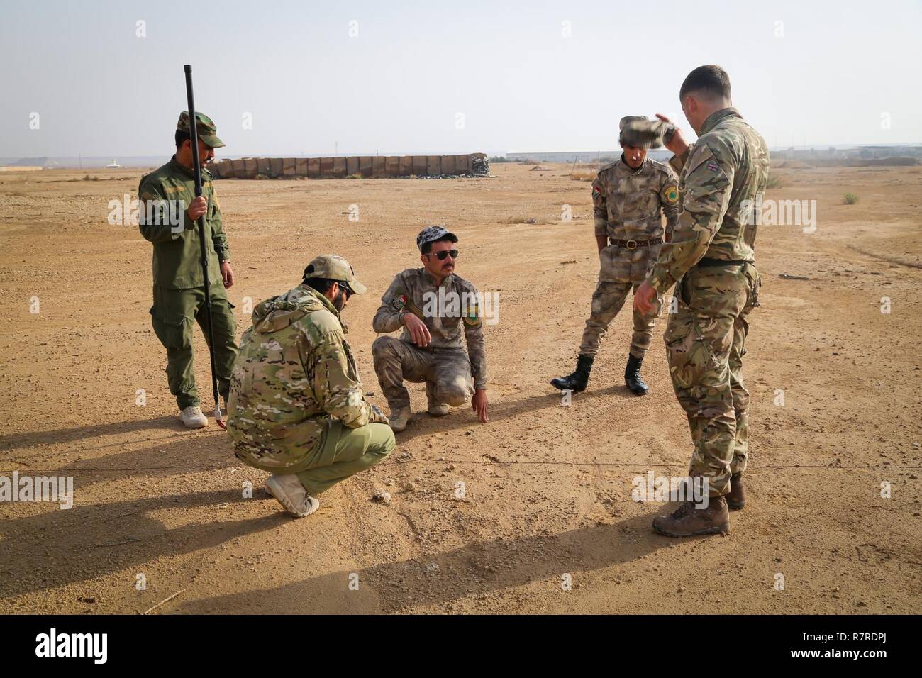 A British trainer, deployed in support of Combined Joint Task Force – Operation Inherent Resolve, explains to Iraqi security forces soldiers how to detect an improvised explosive device on a patrol during counter-IED training at Al Asad Air Base, Iraq, March 29, 2017. This training is part of the overall CJTF- OIR building partner capacity mission by training and improving the capability of partnered forces fighting ISIS. CJTF- OIR is the global Coalition to defeat ISIS in Iraq and Syria. Stock Photo