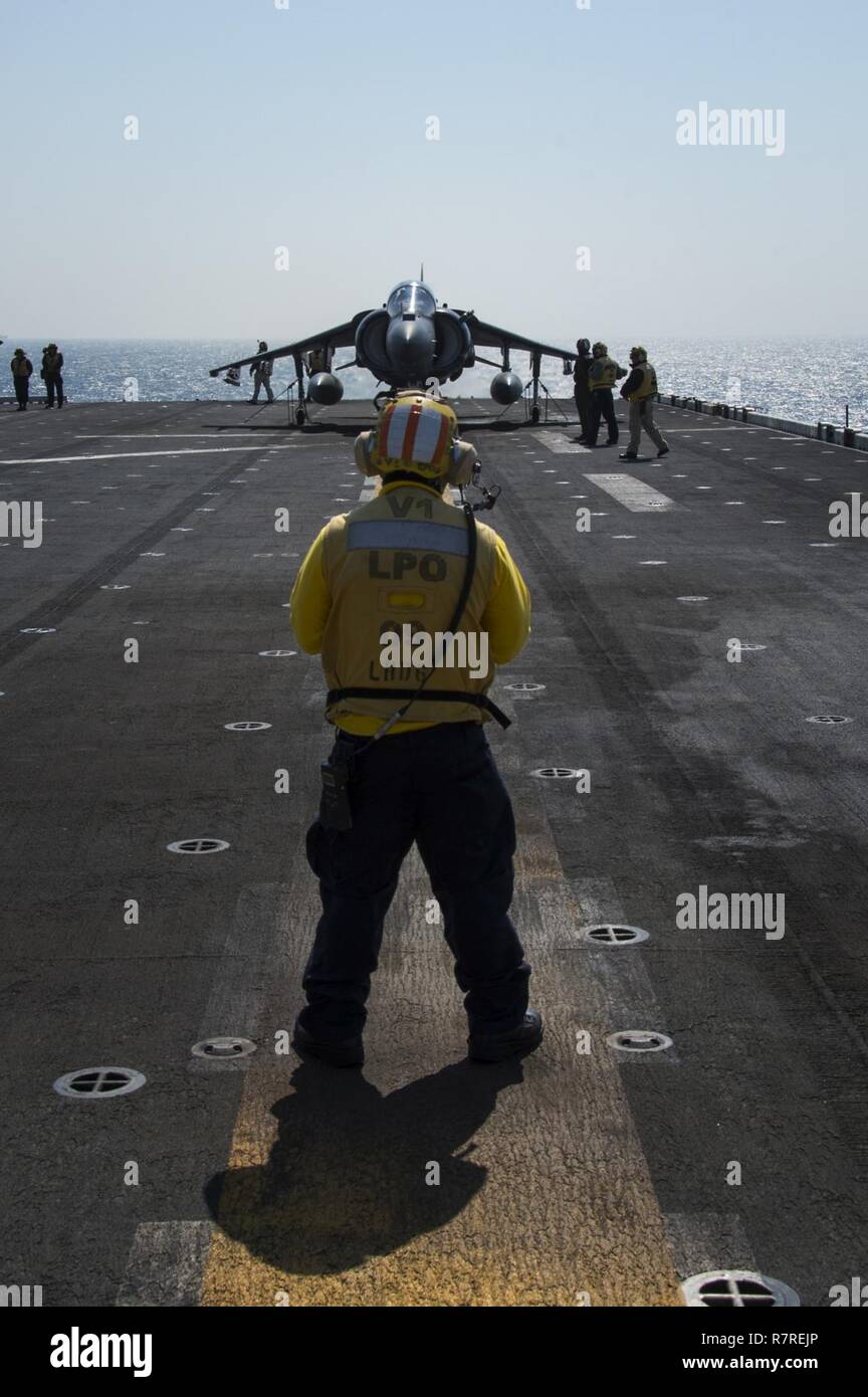 EAST CHINA SEA (April 3, 2017) Aviation Boatswain's Mate (Handling) 1st Class Quoc Nguyen, from San Francisco, directs an AV-8B Harrier, assigned to the 'Tomcats' of Marine Attack Squadron (VMA) 311, into takeoff position during flight operations aboard the amphibious assault ship USS Bonhomme Richard (LHD 6). Bonhomme Richard, flagship of the Bonhomme Richard Expeditionary Strike Group, with embarked 31st Marine Expeditionary Unit, is on a routine patrol, operating in the Indo-Asia-Pacific region to enhance warfighting readiness and posture forward as a ready-response force for any type of co Stock Photo
